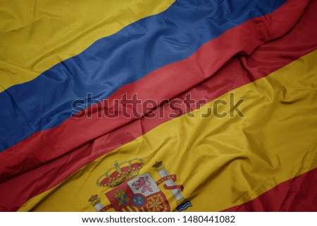 waving colorful flag of spain and national flag of colombia. macro