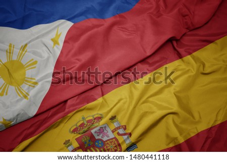 waving colorful flag of spain and national flag of philippines. macro