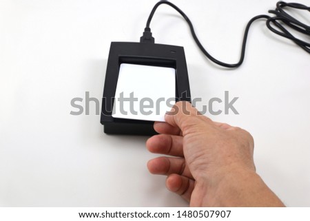 Hand holding white card touch on RFID card reader on white background.