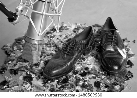 Foley professional studio microphone front dress male shoes over a broken glass floor in a sound record studio. black and white image