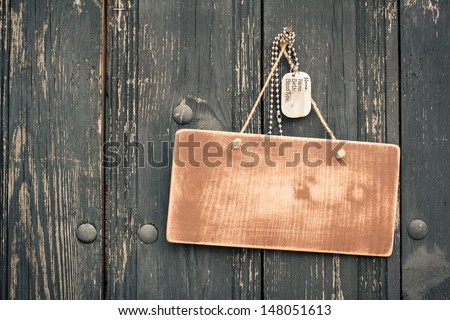 Wooden signboard with army dog tags hanging on wood planks background
