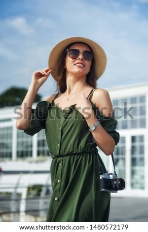 Young woman tourist holding a retro camera . Walking around the city