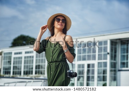 Young woman tourist holding a retro camera . Walking around the city