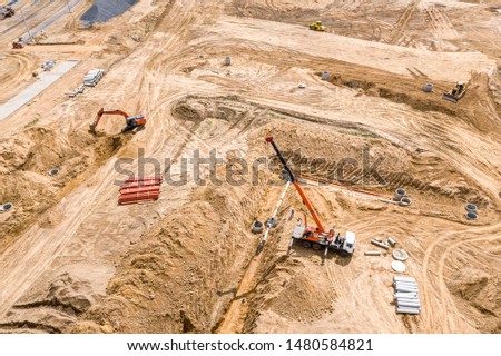 aerial top view of industrial machinery laying concrete pipes for road drainage system