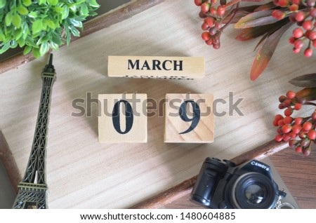 March 9. Date of March month. Number Cube with a flower camera and Sign wood on Diamond wood table for the background.