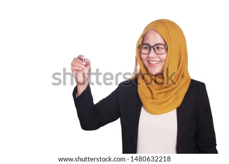 Portrait of young beautiful Asian muslim woman writing something in the air or virtual screen, smiling happy expression