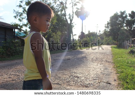 
Little boy walking on the road alone in the countryside, evening and golden sunshine