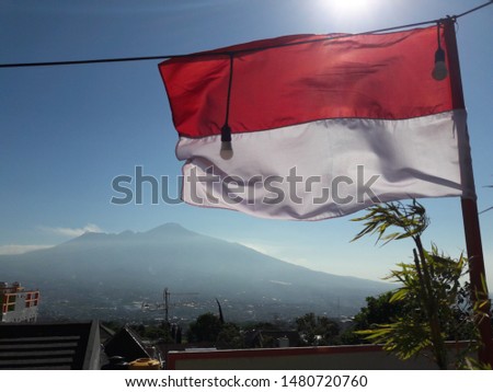Indonesian Flag, Red and White, with blue sky and mountain background