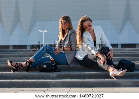 Beautiful girls in a city. Stylish ladies sitting on a stairs Portrait.
