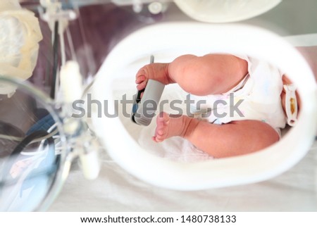 Rescue of newborn children in intensive care. Macro photo of the legs of a child with medical devices. Life saving concept.