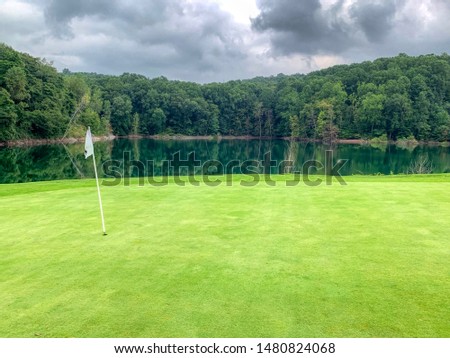 Scenic view of a golf course water hazard with a forest background reflection in the waters just off the green with a flag in the foreground.  Lebanon County, PA. 