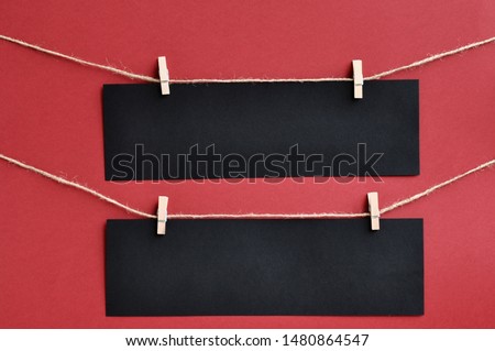Black Friday concept: strips of black paper with space for text attached by clothespins to a rope on a red background.