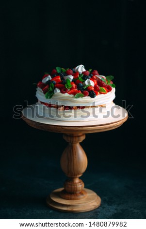 Fruit cake. Cake decorated with berries on a wooden stand on a black background Royalty-Free Stock Photo #1480879982