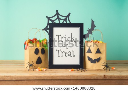 Halloween holiday concept with picture frame, party gift paper bags decor and candy on wooden table