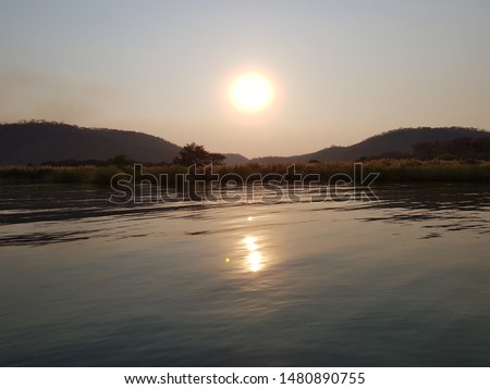 Sunset down Munjela river valley over calm lake