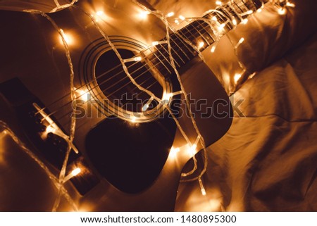 The acoustic guitar is placed on a futon decorated with flashing lights.
