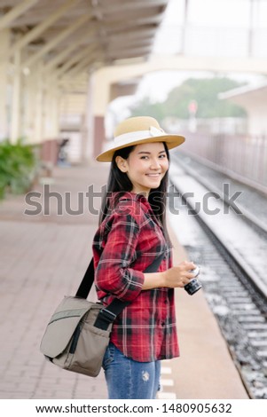 Pretty young woman traveler have fun travel and enjoy taking photo at railway station in evening with vintage camera. The travel photographer takes photo with old vintage camera at train station.