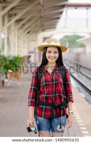 Pretty young woman traveler have fun travel and enjoy taking photo at railway station in evening with vintage camera. The travel photographer takes photo with old vintage camera at train station.