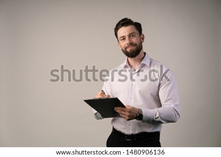 Middle age, 30-40s smiling businessman signing official contract or filling business document with a pen, working in modern office with cup of coffee , close up.