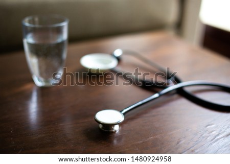 Closeup of  stethoscope on wood table with water glass