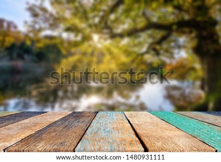 Wood table top on blur abstract natural foliage bokeh background, vintage tone - can be used for display or montage your products