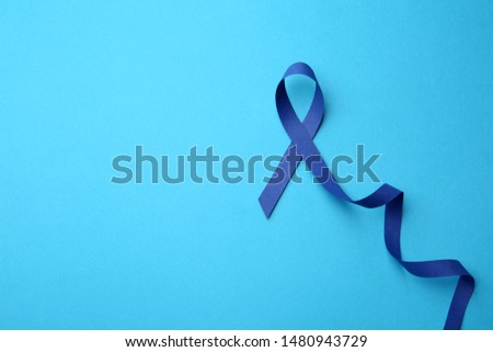 Blue awareness ribbon on color background, top view with space for text. Symbol of social and medical issues