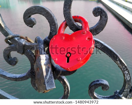 Castle, form of red iron hearts. Closed on the fence forged fence on the bridge. The background behind the water and the waterfront.
