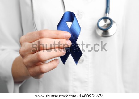 Doctor holding blue awareness ribbon, closeup view. Symbol of medical issues Royalty-Free Stock Photo #1480951676