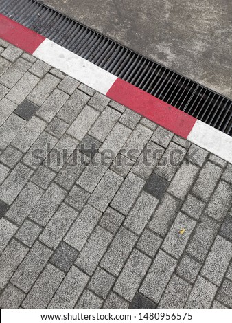 Footpath road. Red and white concrete sidewalk curb . signs on a road.
