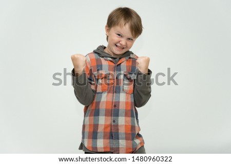 Photo portrait waist-high of a fun cheerful cute happy school-age boy. Rejoices, smiles on a white background. Shows hands.