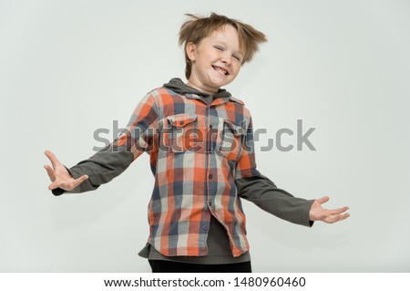 Photo portrait waist-high of a fun cheerful cute happy school-age boy. Rejoices, smiles on a white background. Shows hands.