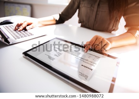 Close-up Of A Busineswoman's Hand Working With Invoice On Digital Tablet Royalty-Free Stock Photo #1480988072
