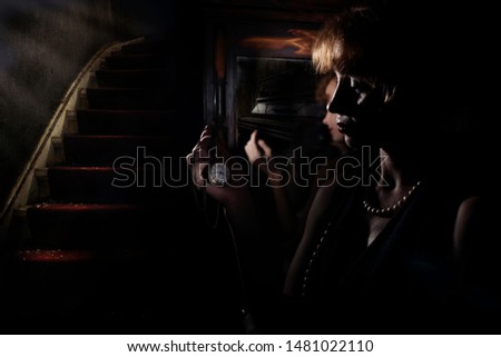 red-haired girl is reflected in the mirror against the background of the old piano
