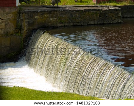 Water falls over old mill dam in Warwick New York in sunset, soothing, glistening
