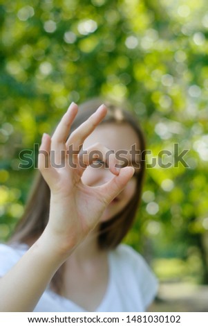 Young teen age girl showing o.k sign, happy thumbs up gesture with hand. Approving expression looking at the camera.