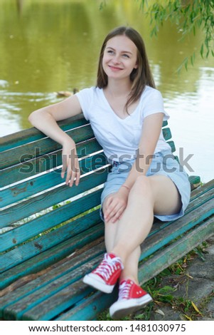 Teenage girl sitting, relaxing in the park, on a bench. summer, school holidays. 