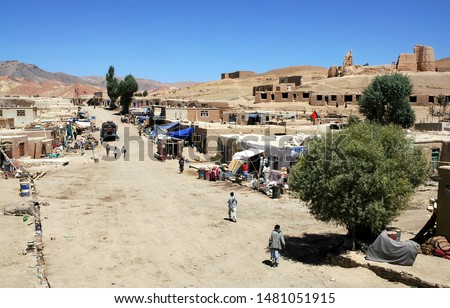 Lal Wa Sarjangal, Ghor Province in Central Afghanistan. This is the dusty main street in Lal. The low basic buildings and dirt road are typical in remote towns in Afghanistan. Note the Afghan flag. Royalty-Free Stock Photo #1481051915