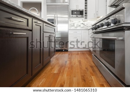 Brown / Espresso and white modern kitchen cabinets with shaker door style and stainless steel appliances with hardwood floors Royalty-Free Stock Photo #1481065310