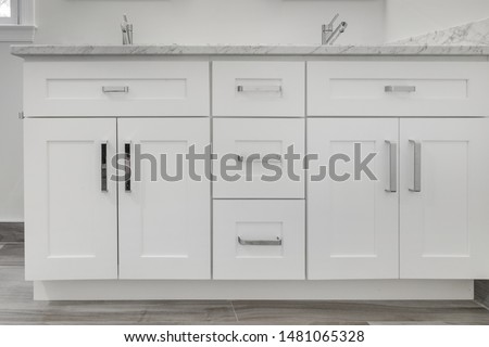White shaker style bathroom vanity with drawers and polished chrome handles, vanity top and chrome faucets Royalty-Free Stock Photo #1481065328