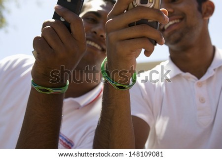 Two young men holding mobile phones outdoors
