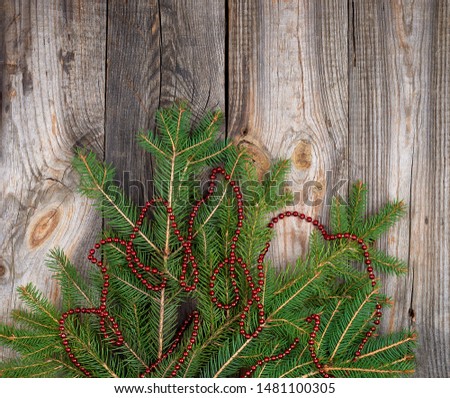 green branches of needles and red Christmas garland on a gray wooden background from boards, copy space