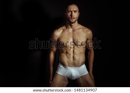 Strong stripped muscle male model in white underwear on black isolated font background