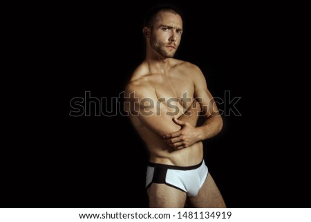 Strong stripped muscle male model in white underwear on black isolated font background