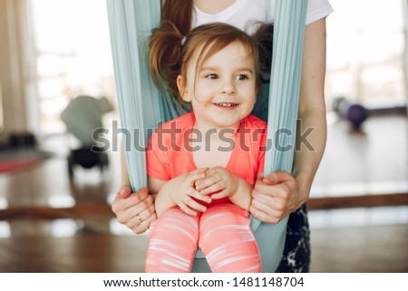 Woman in a sportswear. Mother with little daughter. Family are engaged in gymnastics in a gym