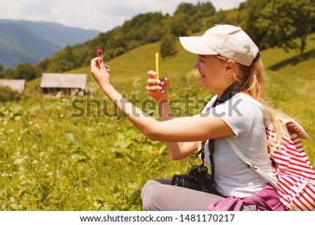 Young woman taking selfie photo on smartphone in the forest on a sunny summer day.