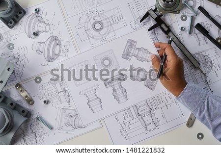 Engineer technician designing drawings mechanical parts engineering Enginemanufacturing factory Industry Industrial work project blueprints measuring bearings caliper tools Royalty-Free Stock Photo #1481221832