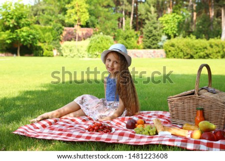 Little girl enjoying picnic on green lawn