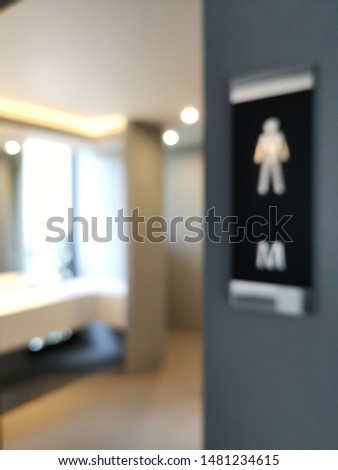 Side view and focus on white male restroom sign on wall decorations with flare light and blurred restroom inside area background