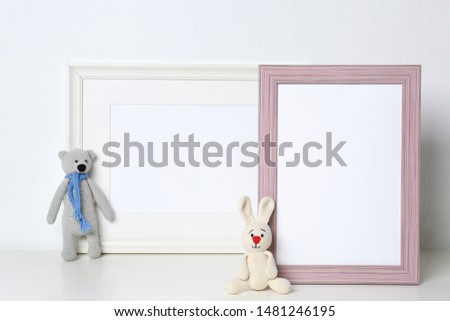 Soft toys and photo frames on table against white background, space for text. Child room interior