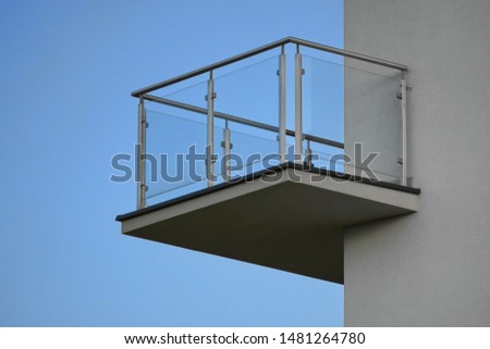 one balcony with glass railing against the blue sky on Sunny day. bottom view, modern building design, Scandinavian style with white walls Royalty-Free Stock Photo #1481264780